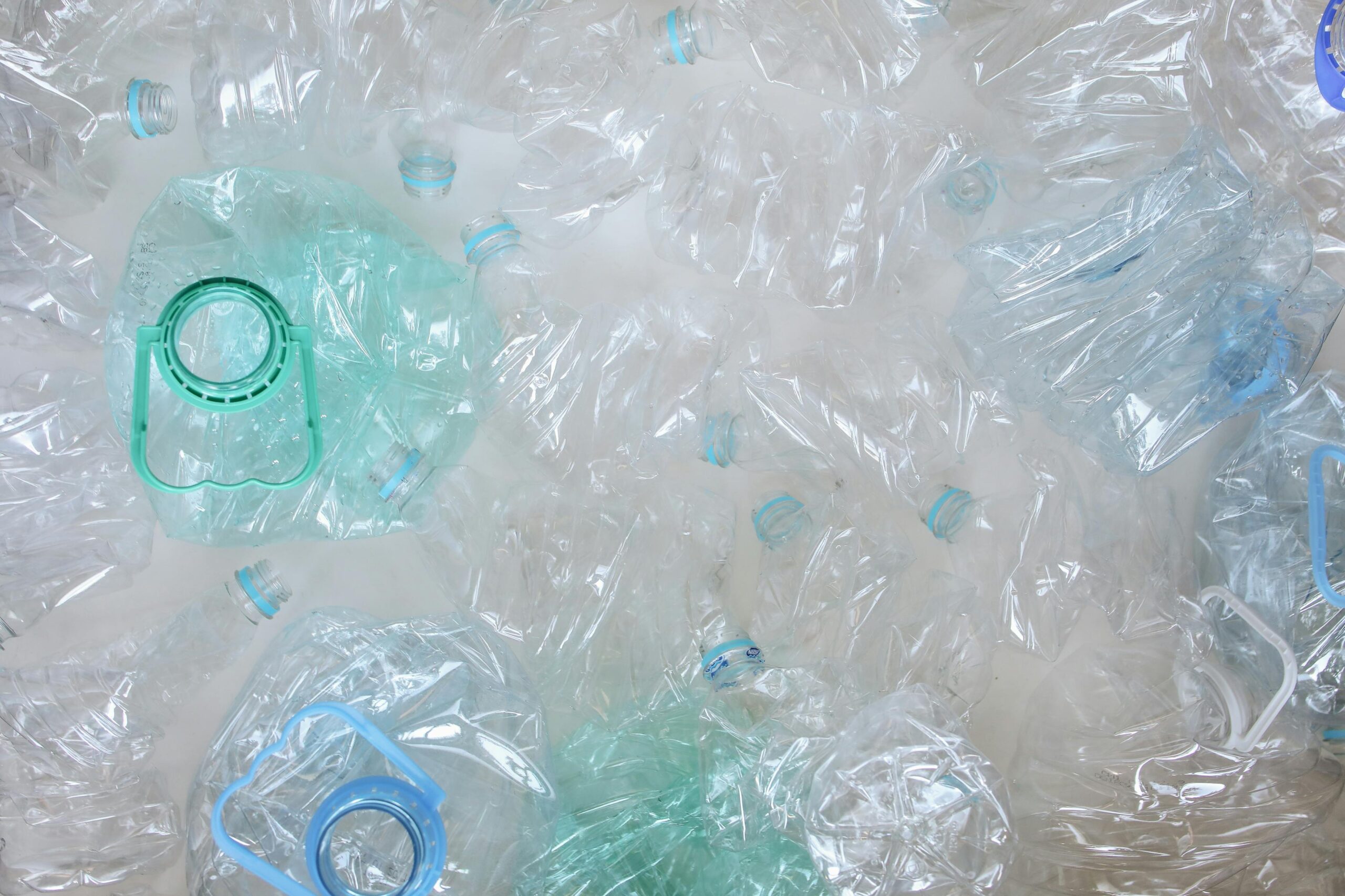 Top-view of crushed plastic bottles prepared for recycling, promoting sustainability.
